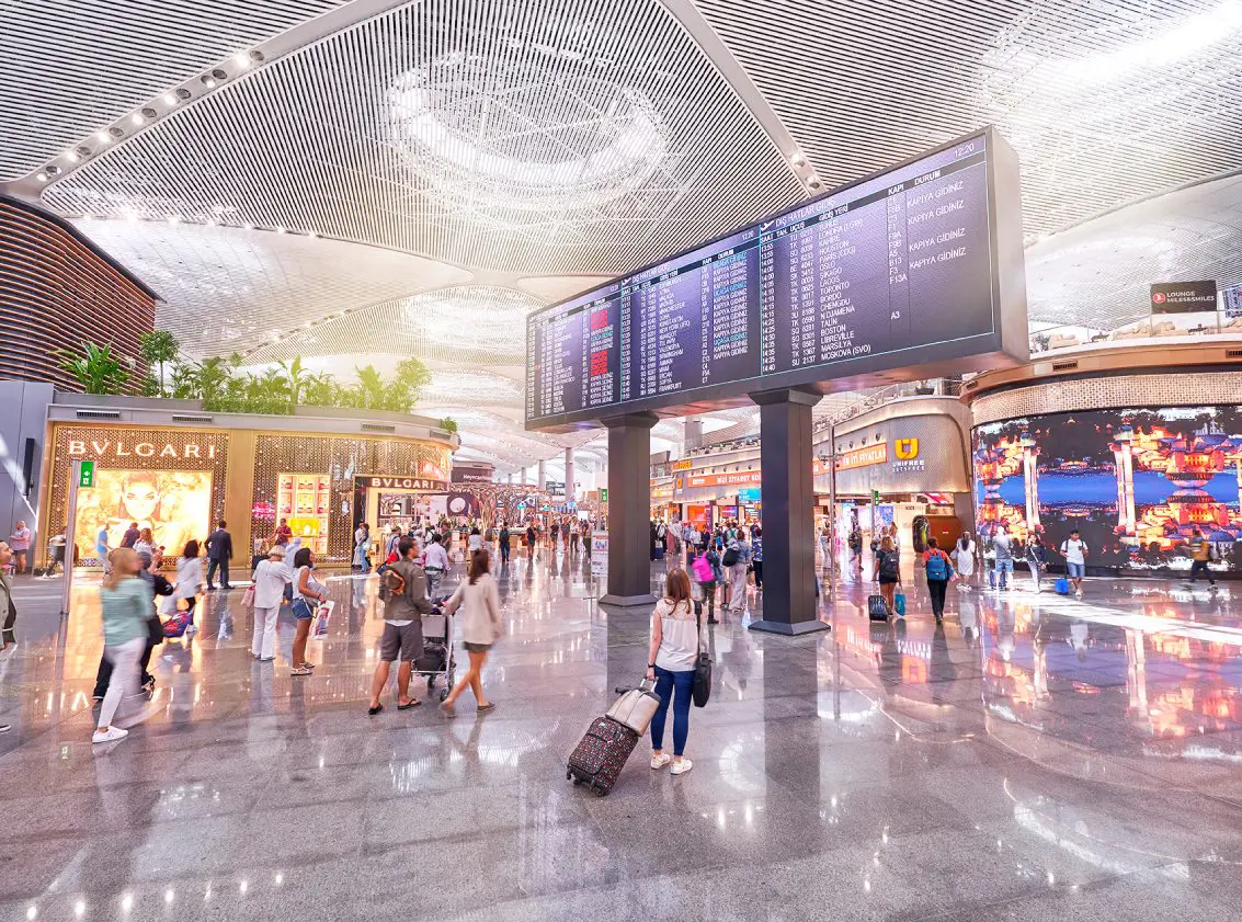 flight screen and passengers in the airport shopping zone